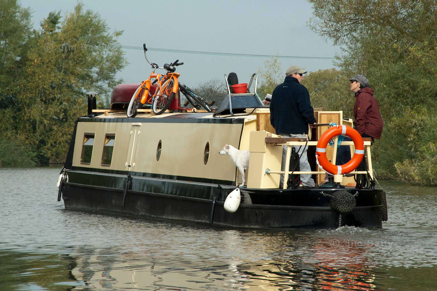 Two women and their dog cruising on the stern of their narrowboat